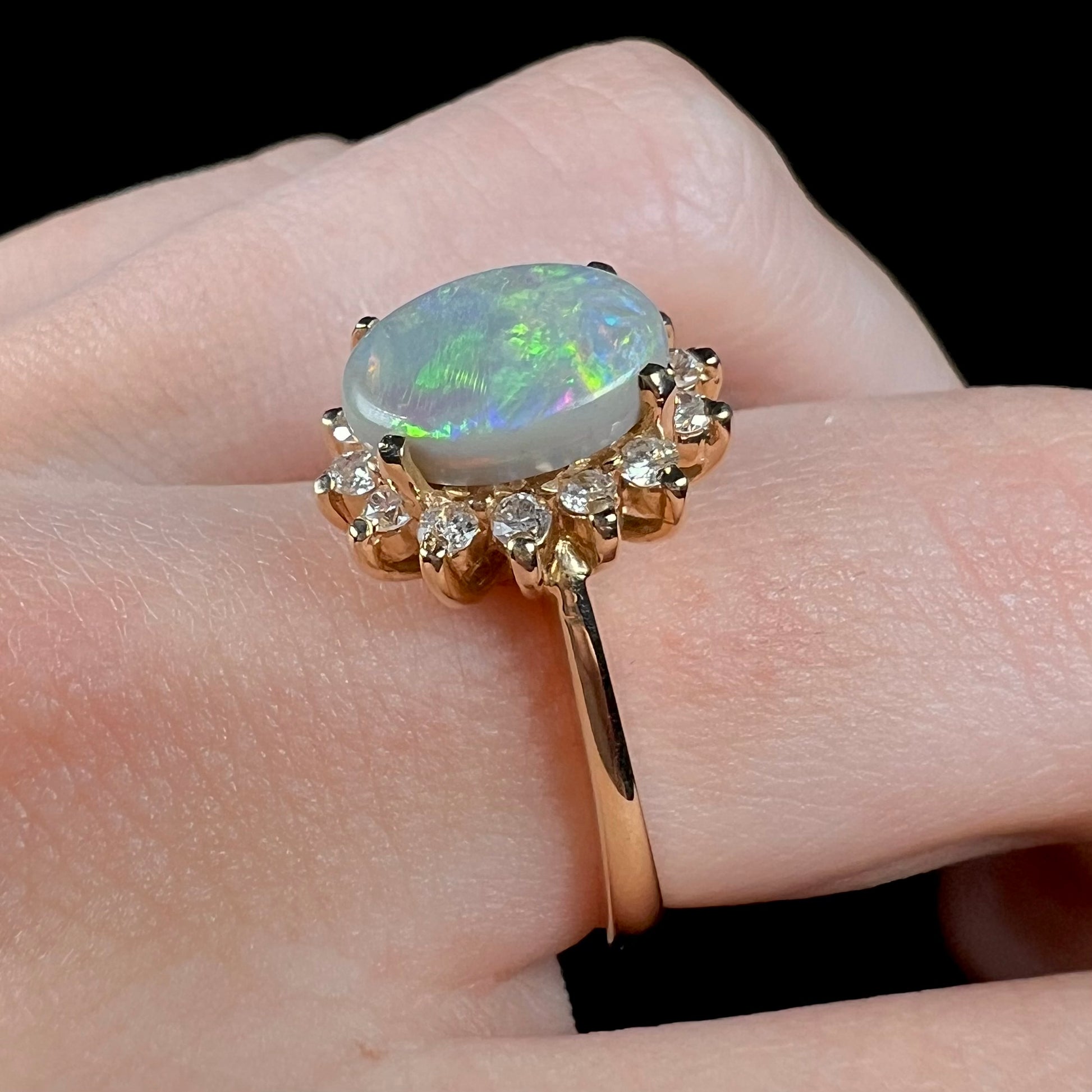 A yellow gold ring mounted with a Lightning Ridge semi-black opal.  The opal is surrounded by round diamonds.