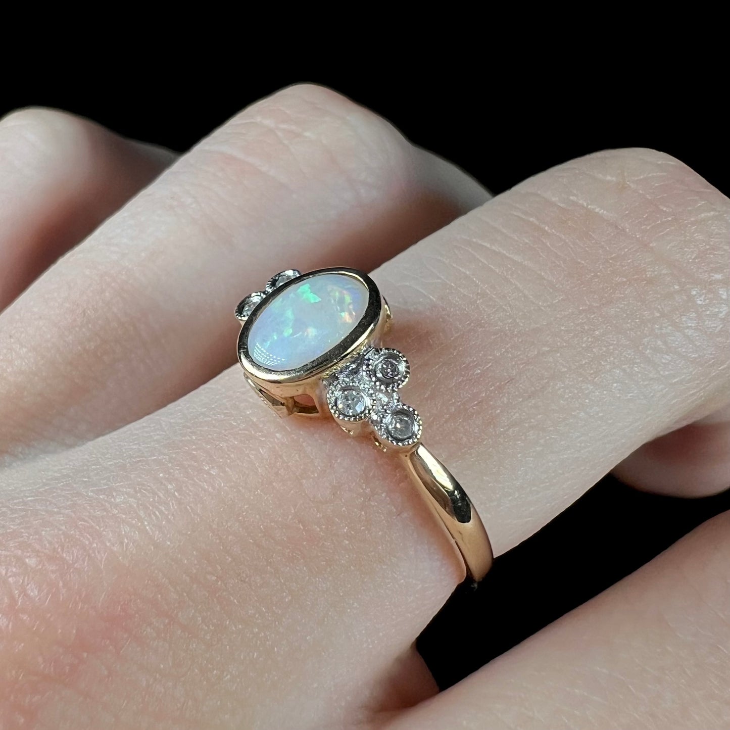 A ladies' yellow gold opal ring.  Three diamonds are set on each side of the opal.  Two rubies are set under the opal.