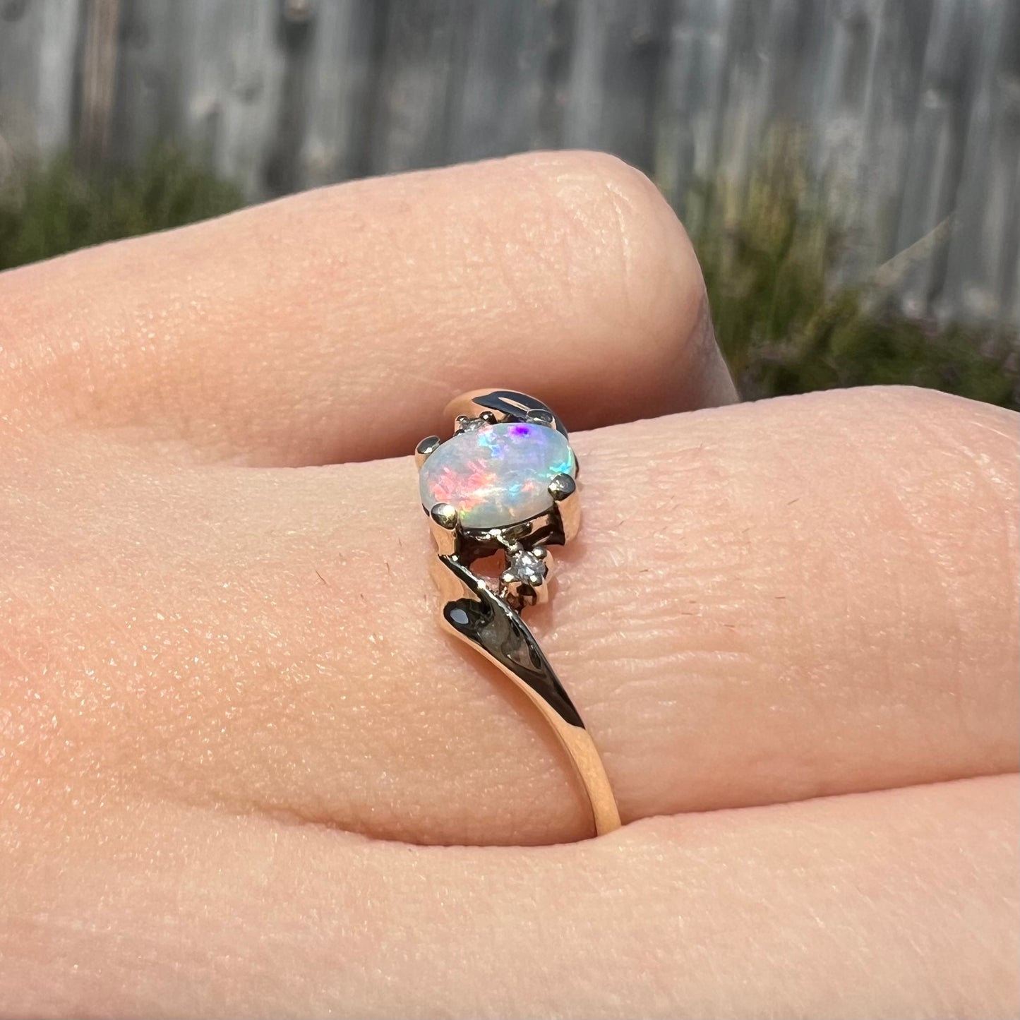 An oval cabochon cut opal and diamond engagement ring in yellow gold.