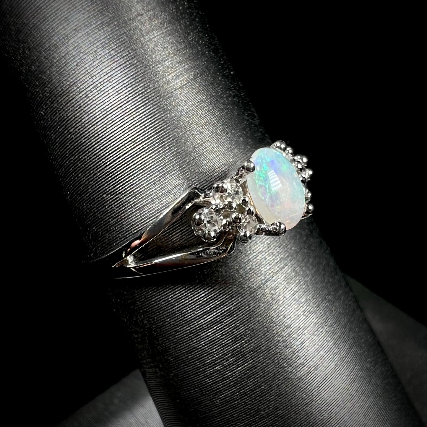 A ladies' white gold opal ring mounted with round diamond accents.