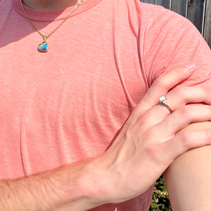 A ladies' yellow gold opal ring.  Three diamonds are set on each side of the opal.  Two rubies are set under the opal.