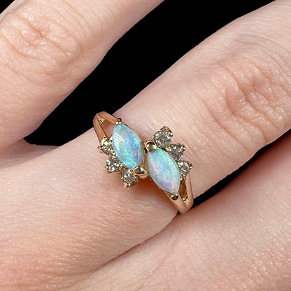 A yellow gold ring mounted with two marquise cut opals and accented with six round diamonds.