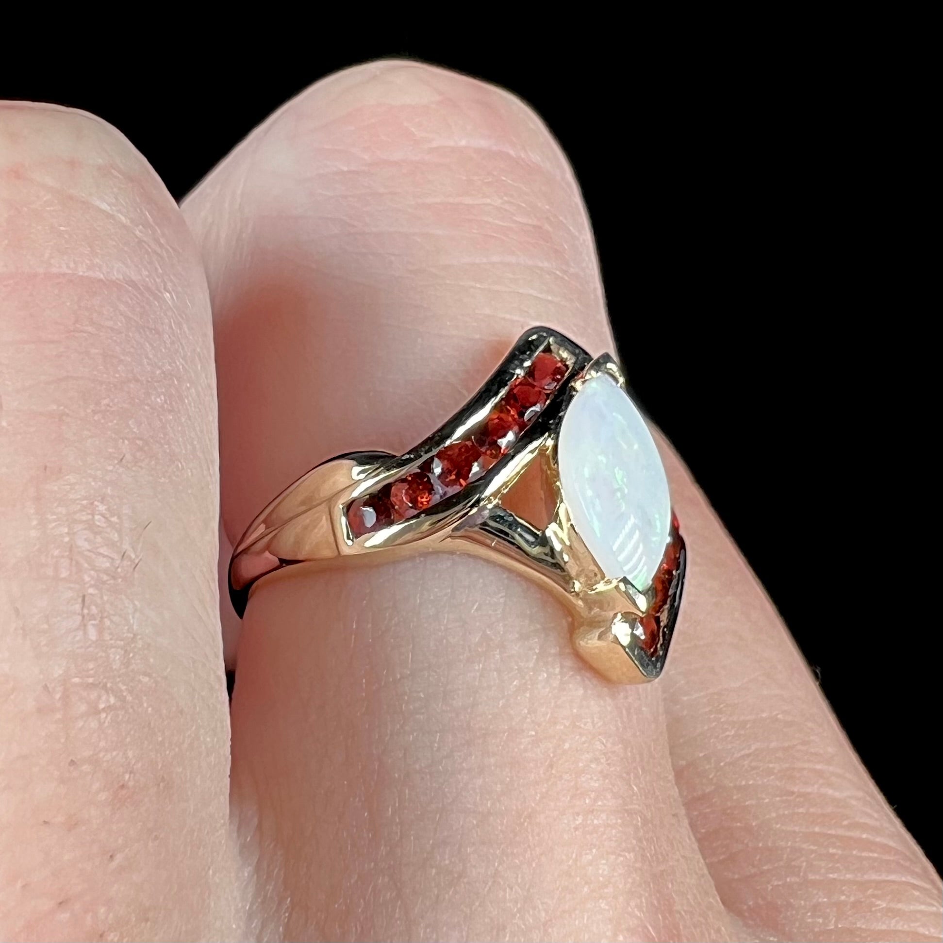 A marquise cut white opal ring.  The ring is accented with channel set reddish orange garnets.