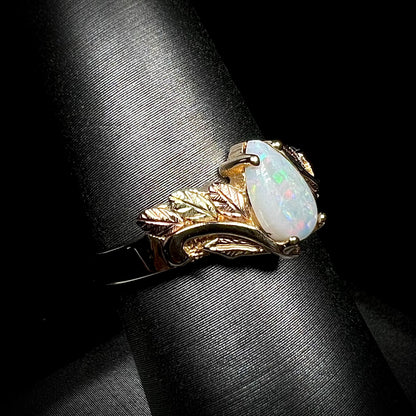 A ladies' two-tone yellow and rose Black Hills gold opal and diamond ring.  The opal is a pear shaped cabochon.