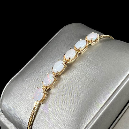 A 14 karat yellow gold bracelet mounted with oval cabochon cut natural opals.