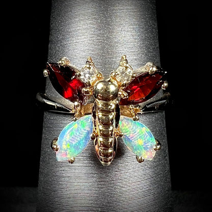 A yellow gold butterfly ring mounted with marquise cut garnets and opals and round diamond accents.