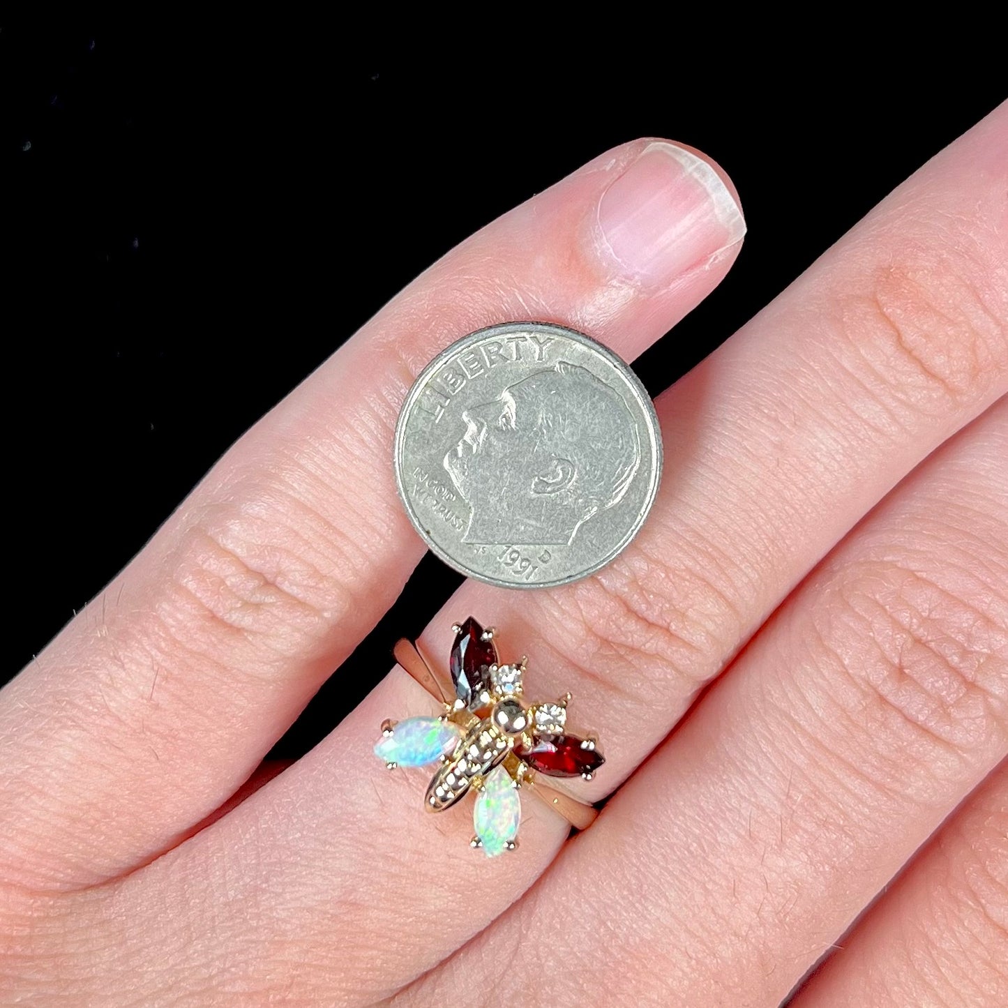 A yellow gold butterfly ring mounted with marquise cut garnets and opals and round diamond accents.