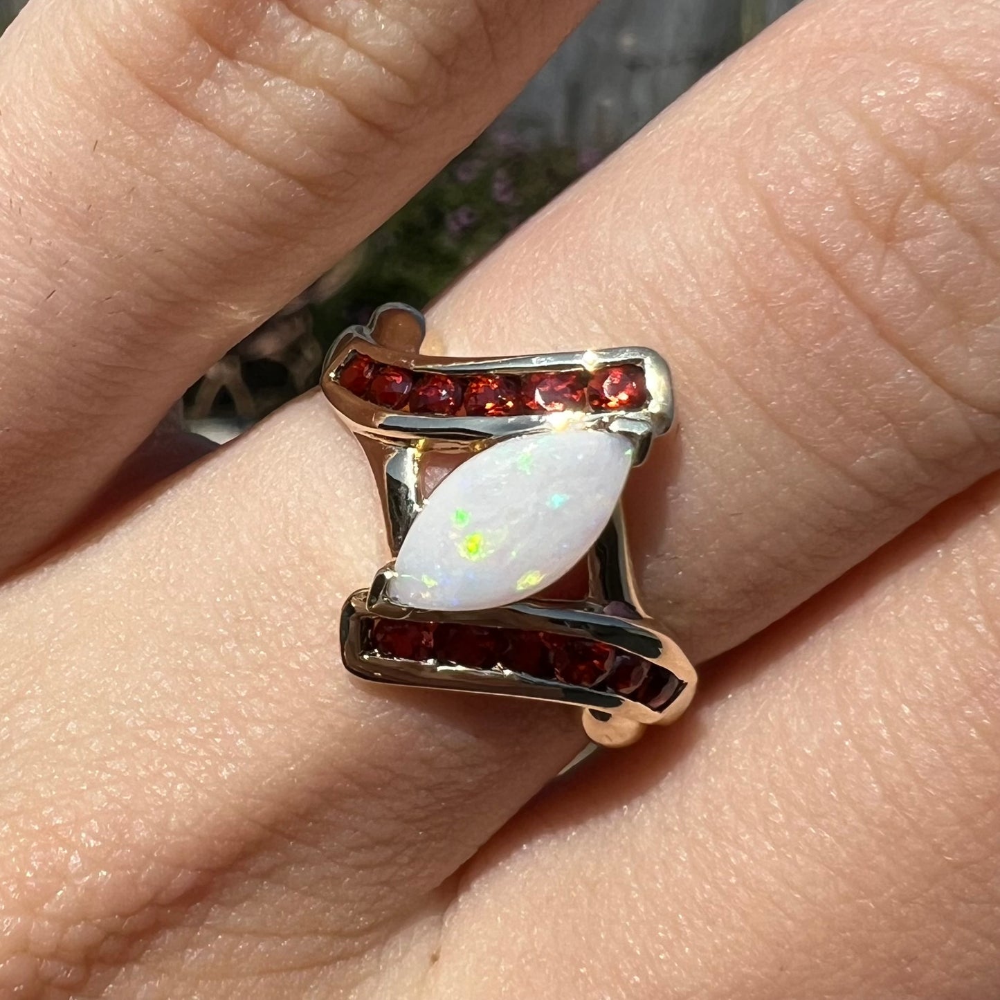 A marquise cut white opal ring.  The ring is accented with channel set reddish orange garnets.