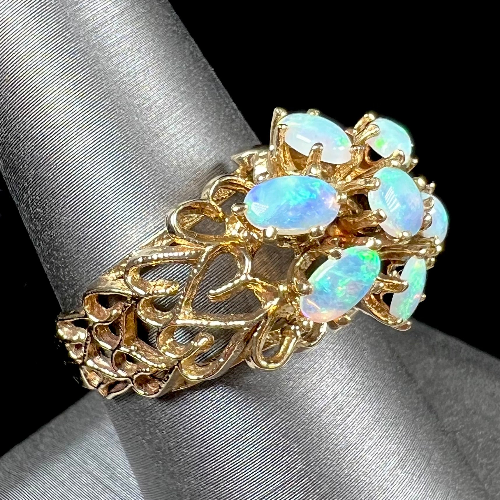 A vintage, 1950's style opal cluster ring cast in yellow gold with a heart shaped filigree design.