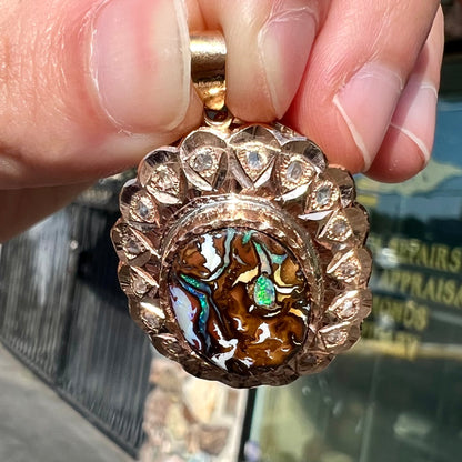 An antique 18 karat yellow gold pendant set with rough diamonds and an oval cut boulder opal from Koroit, Australia.