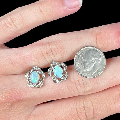 A pair of white gold flower stud earrings with diamonds mounted in the petals and opals set in the center.