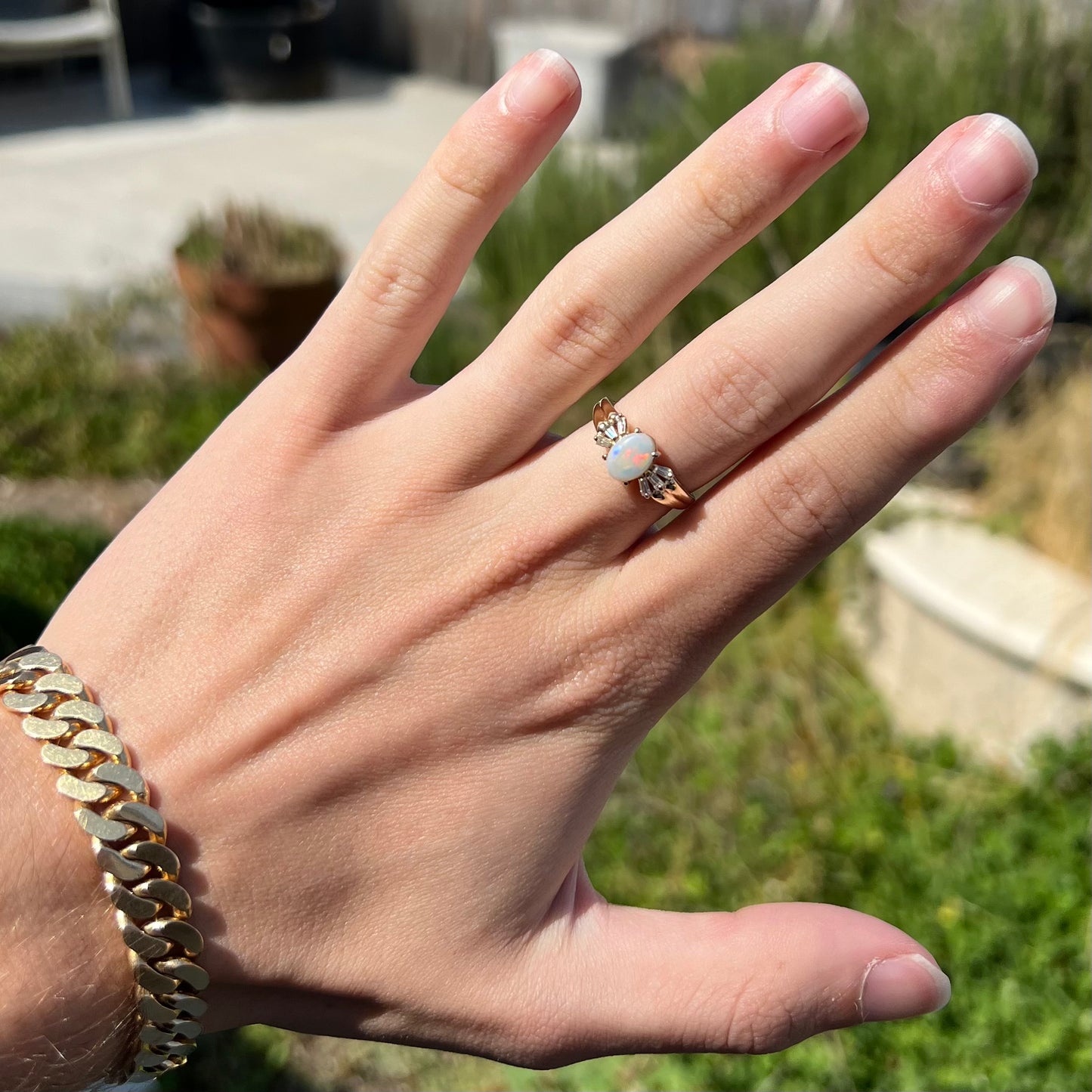 A yellow gold ring set with a natural Australian opal and tapered baguette cut cubic zirconia accents.