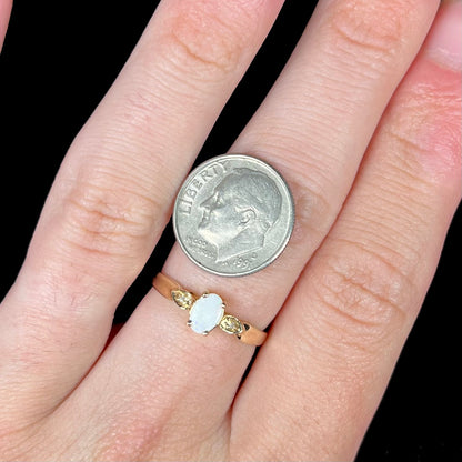 A dainty ladies' yellow gold opal and diamond ring.  The opal has subtle play of color.