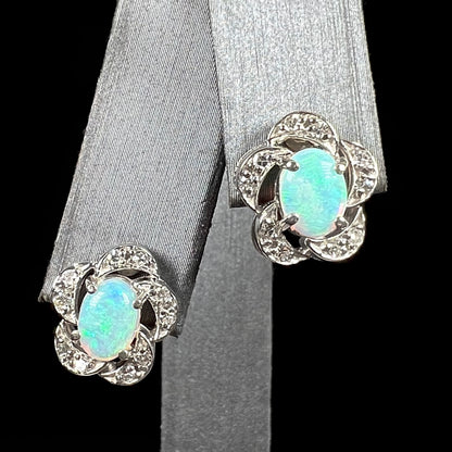 A pair of white gold flower stud earrings with diamonds mounted in the petals and opals set in the center.