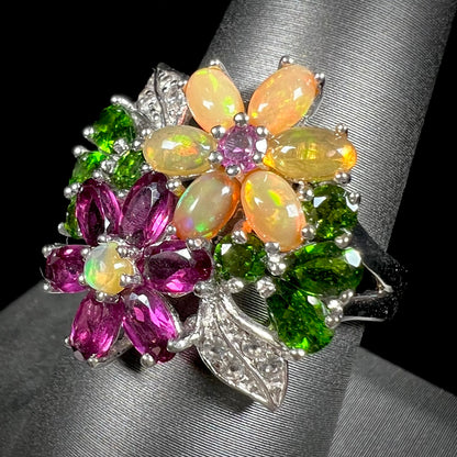 A ladies' gemstone flower design cluster ring set with Ethiopian fire opals, chrome diopsides, rhodolite garnets, and white topaz stones.