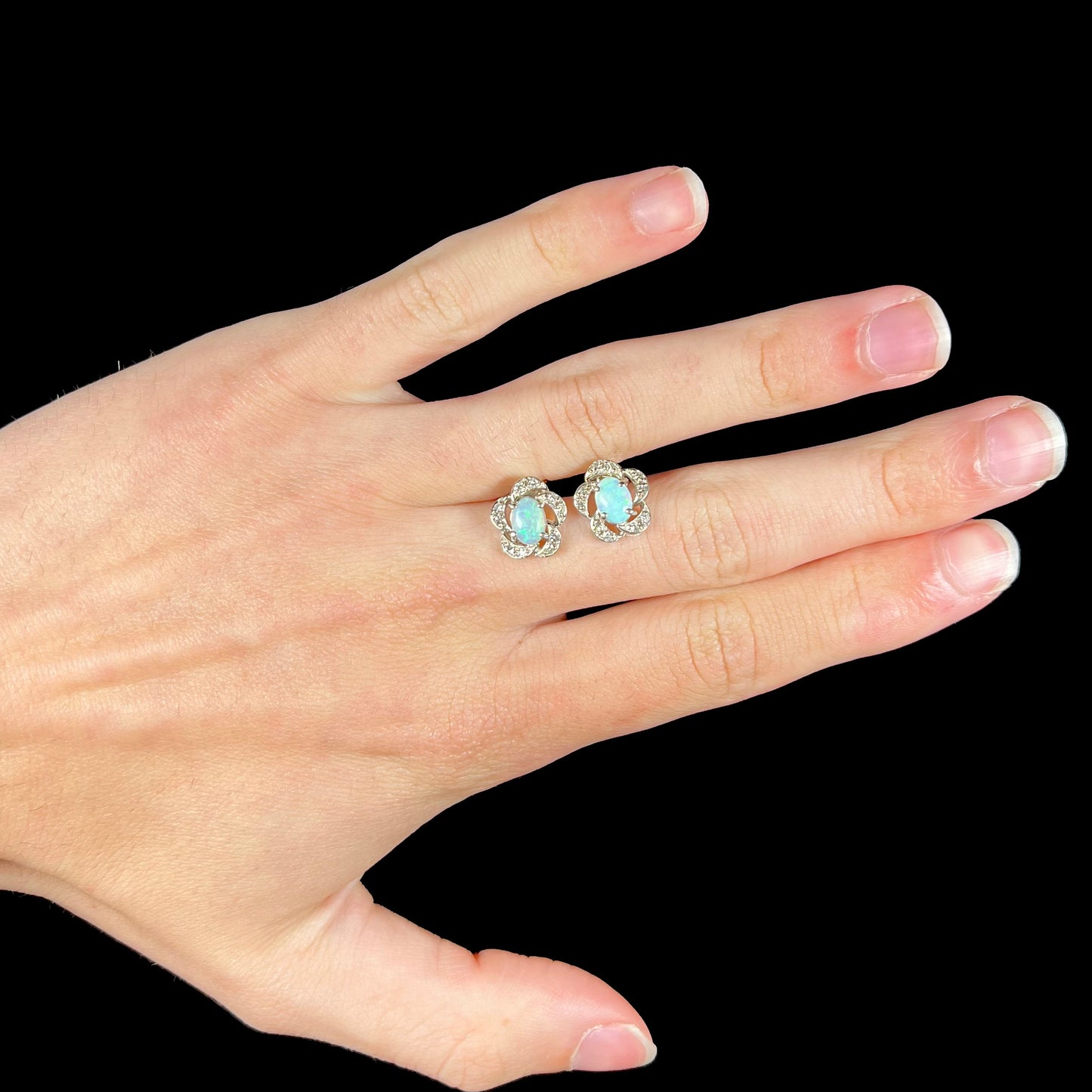 A pair of white gold flower stud earrings with diamonds mounted in the petals and opals set in the center.