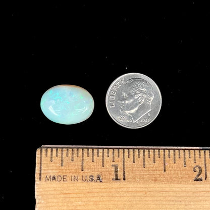 An oval cabochon cut white opal stone from Coober Pedy, Australia.  The opal has subtle colors of green and blue.