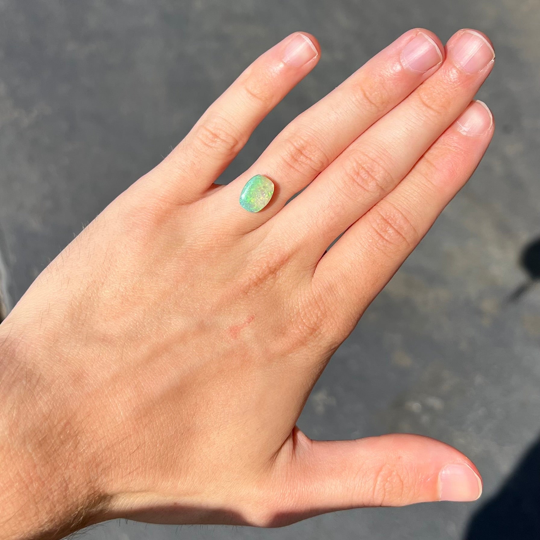 A 2.40ct barrel shaped Lightning Ridge semi-crystal opal.  The stone has blue and green colors.