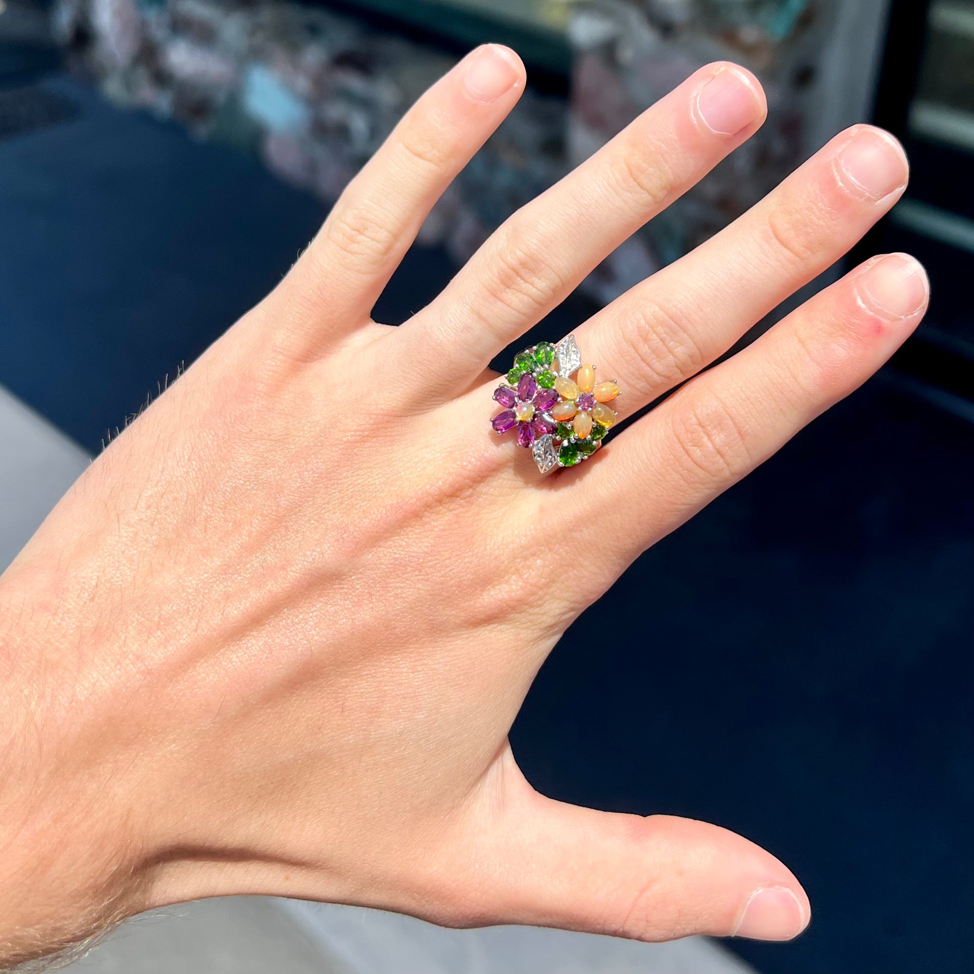 A ladies' gemstone flower design cluster ring set with Ethiopian fire opals, chrome diopsides, rhodolite garnets, and white topaz stones.