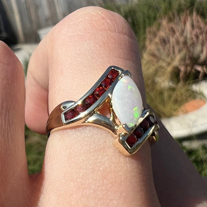 A marquise cut white opal ring.  The ring is accented with channel set reddish orange garnets.