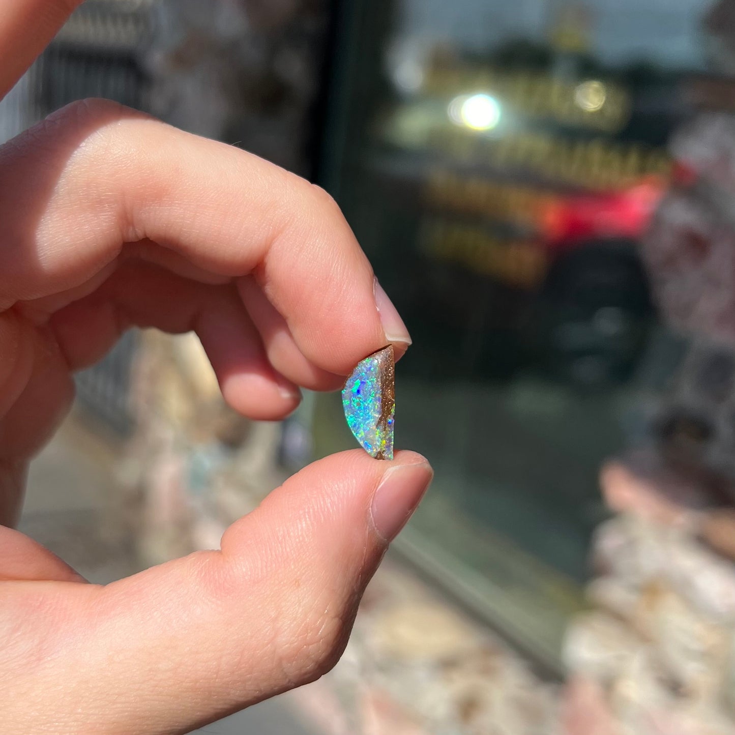 A freeform shaped boulder opal stone from Quilpie, Australia.  The opal has bright blue and green play of color.