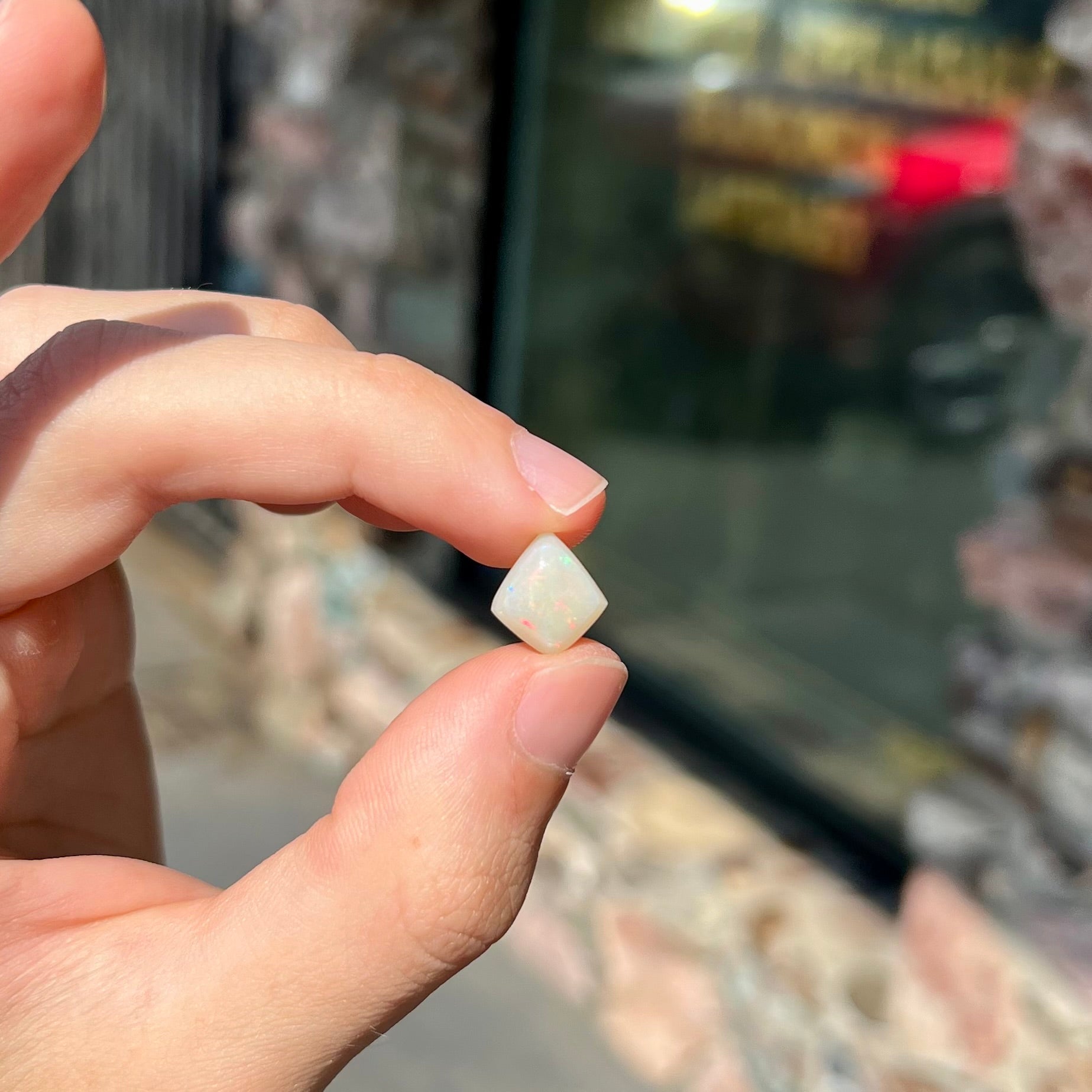 A loose, kite shaped white opal stone from Coober Pedy, Australia.  The stone has subdued red colors.