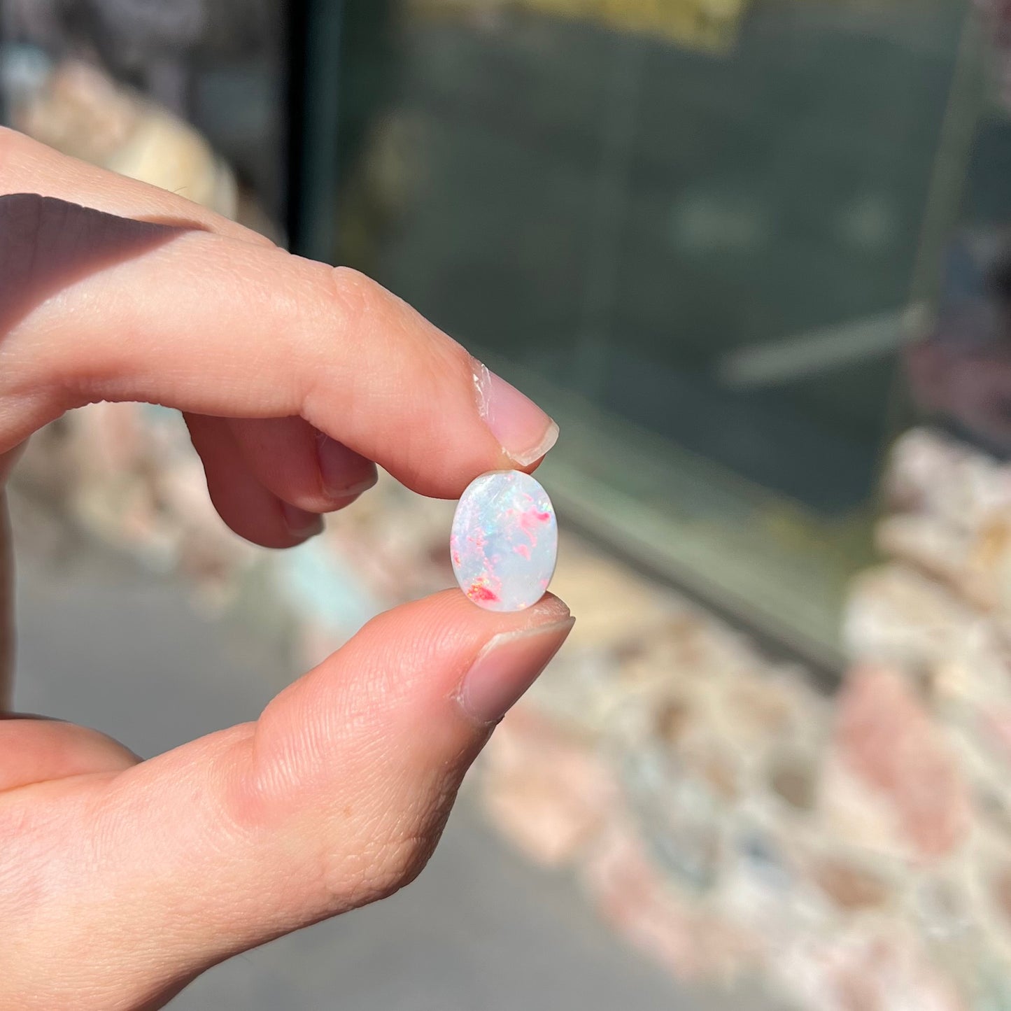 A loose oval cut opal stone from Lightning Ridge, Australia.  The opal shines pinkish red colors.