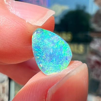 A loose, pear shaped black opal from LIghtning Ridge, Australia.  The opal shines blue and green colors.