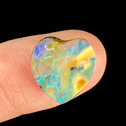 A loose, 5.90 carat heart shaped boulder opal stone from Quilpie, Australia.  The opal has blue flashes.