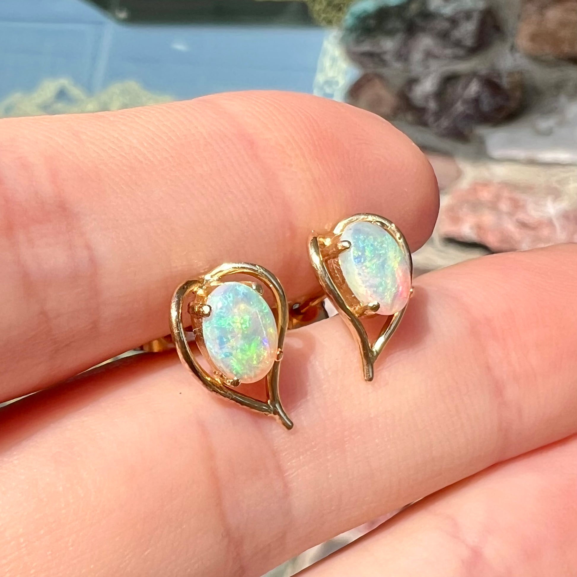 A pair of yellow gold, heart shaped stud earrings set with oval cabochon cut natural opal stones.