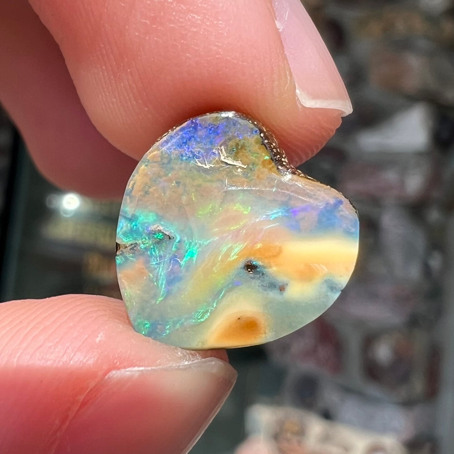 A loose, 5.90 carat heart shaped boulder opal stone from Quilpie, Australia.  The opal has blue flashes.