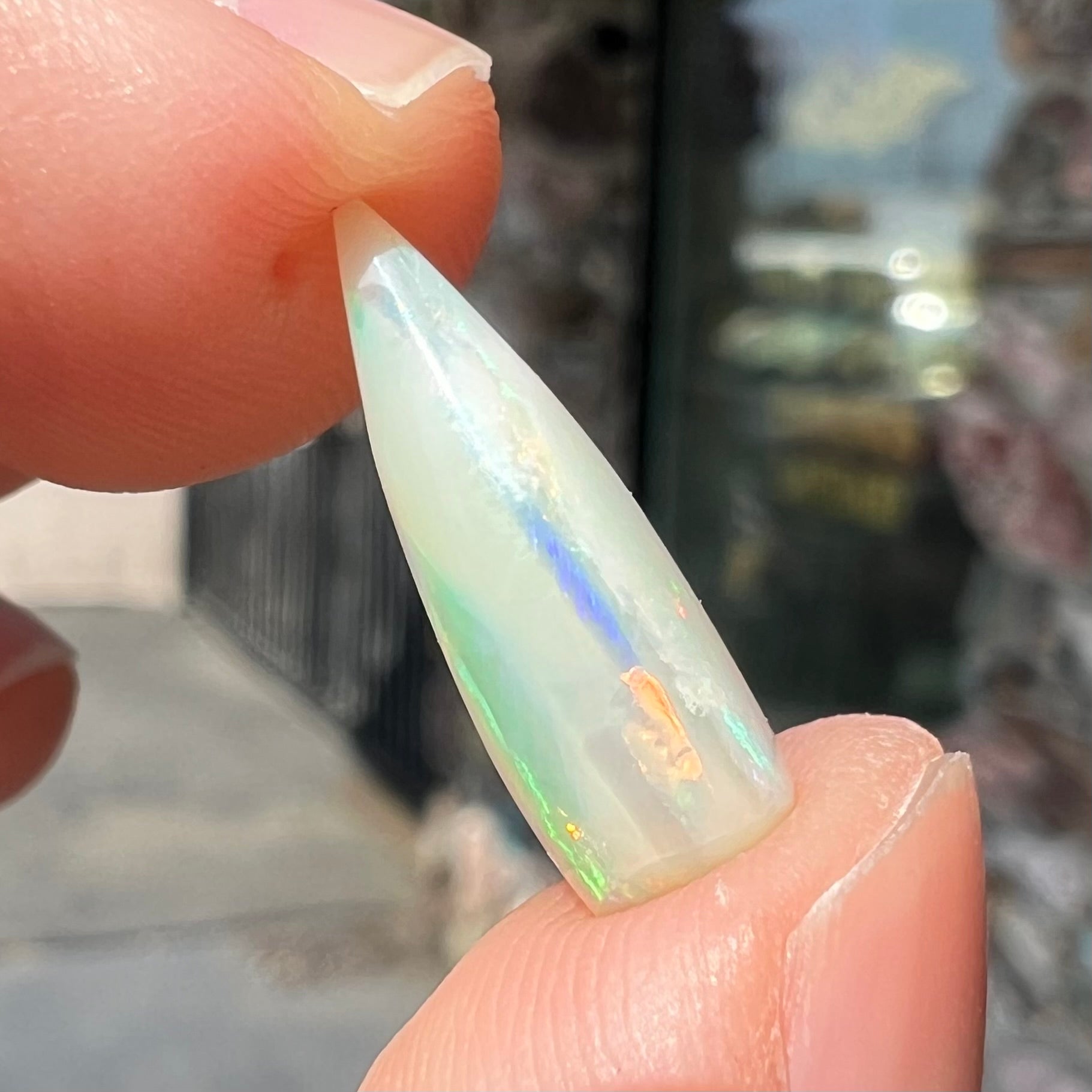 An opalized belemnite fossil from Coober Pedy, Australia.  The specimen has red, yellow, and green play of color.