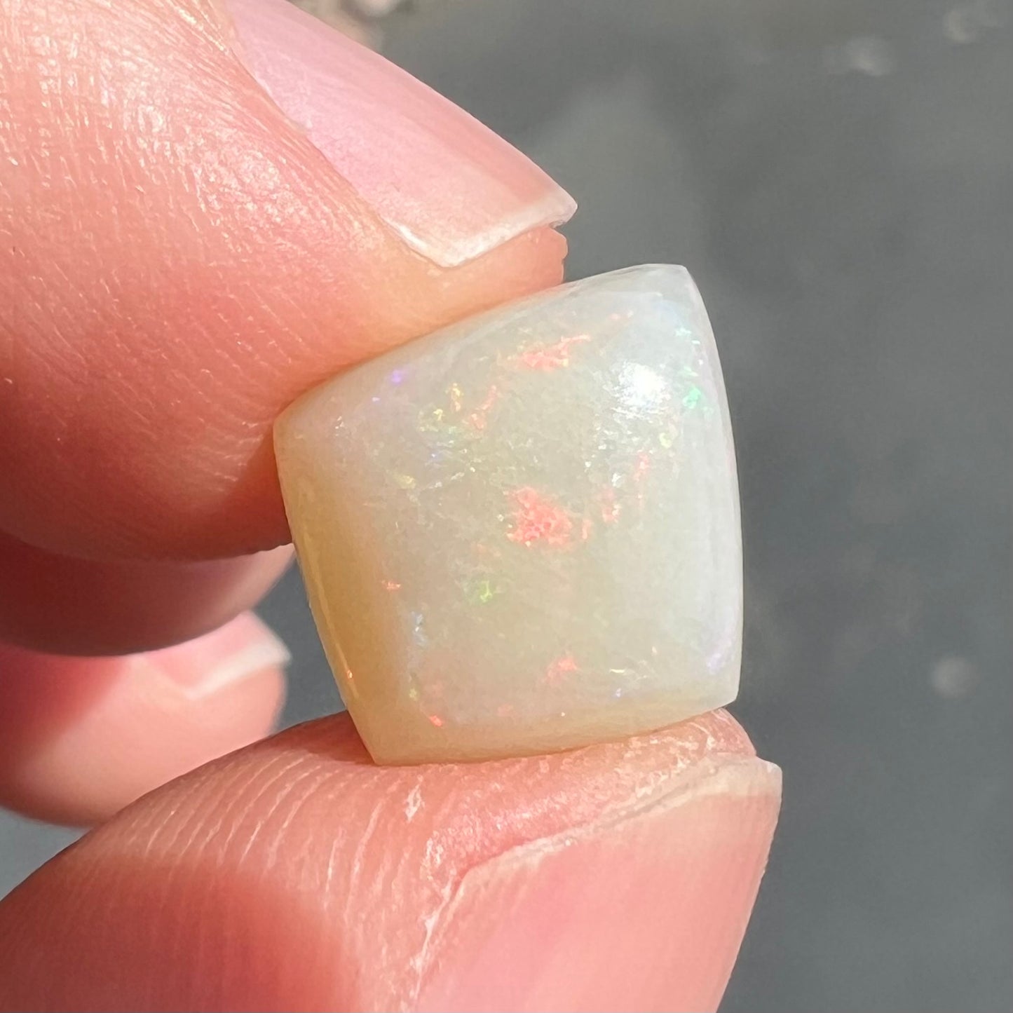 A loose, kite shaped white opal stone from Coober Pedy, Australia.  The stone has subdued red colors.