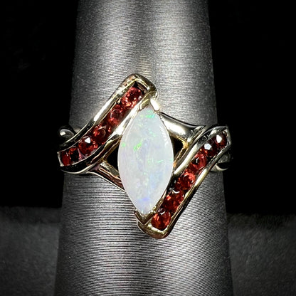 A marquise cut white opal ring.  The ring is accented with channel set reddish orange garnets.