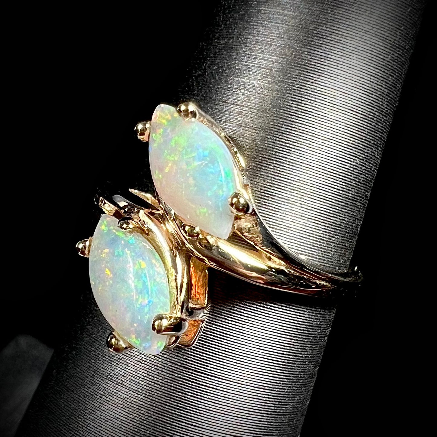 A yellow gold ring mounted with two prong-set marquise cut opal cabochons.