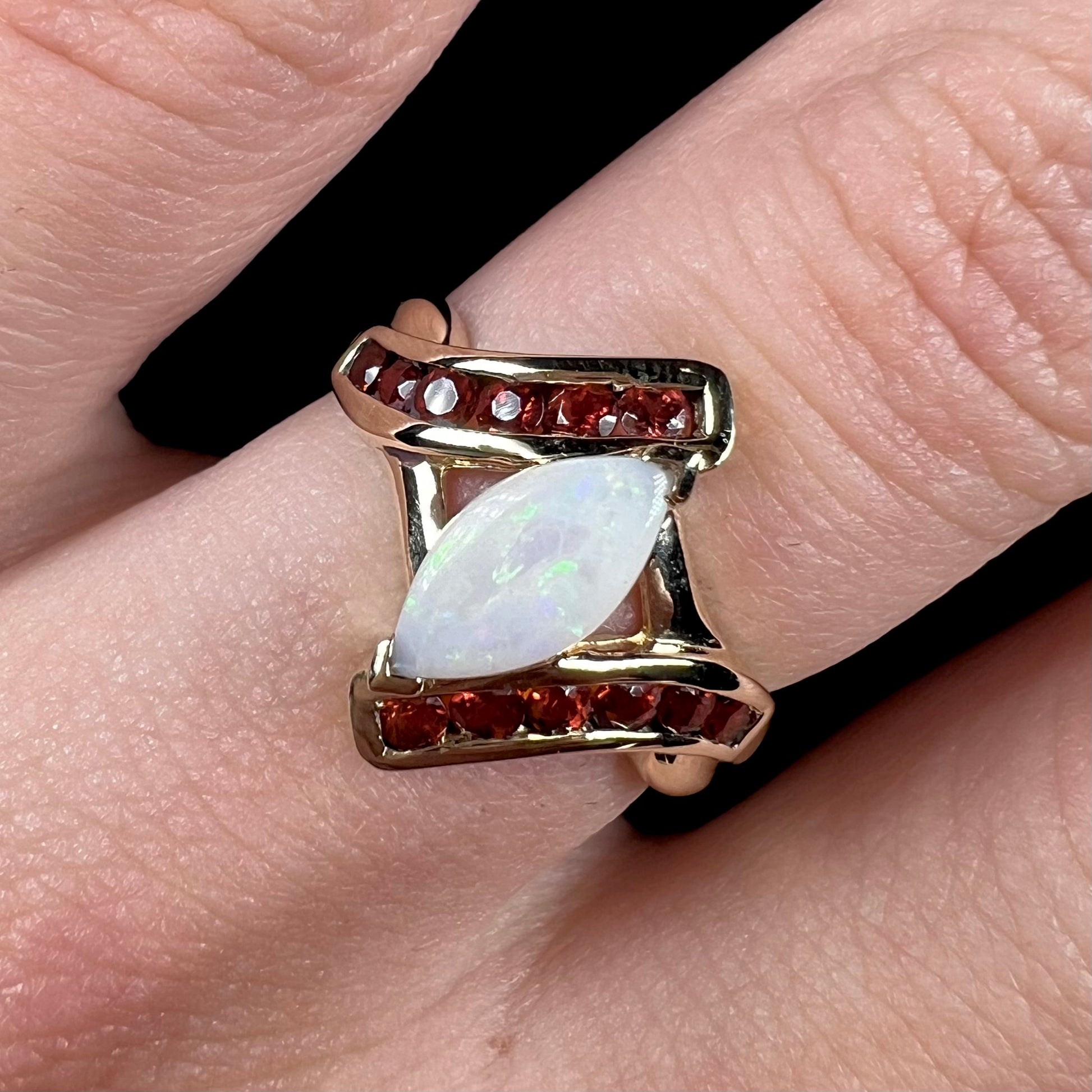 A marquise cut white opal ring.  The ring is accented with channel set reddish orange garnets.