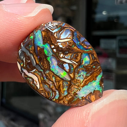 A loose, pear shaped boulder opal stone from Koroit, Australia that has vivd green and blue veins of color.