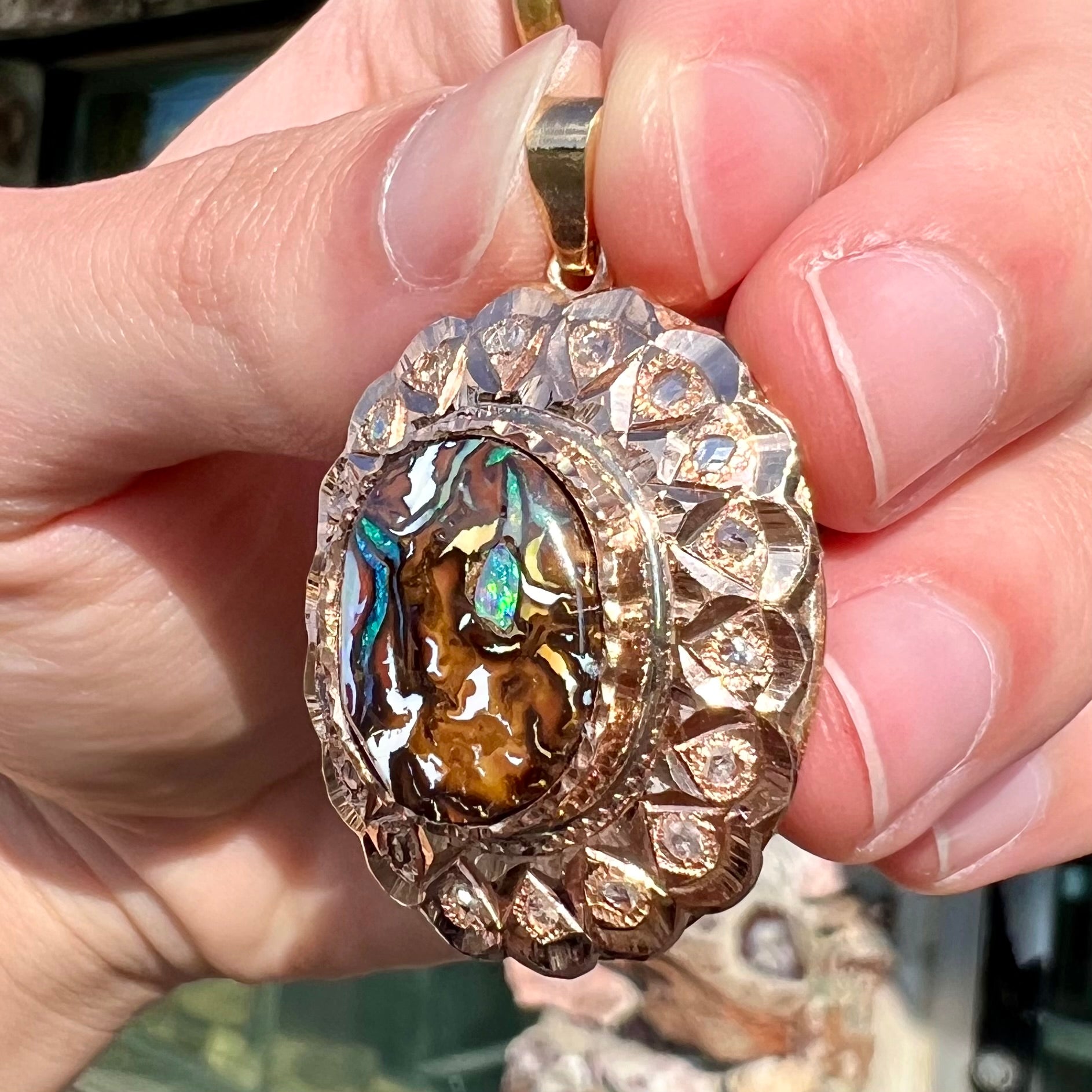 An antique 18 karat yellow gold pendant set with rough diamonds and an oval cut boulder opal from Koroit, Australia.