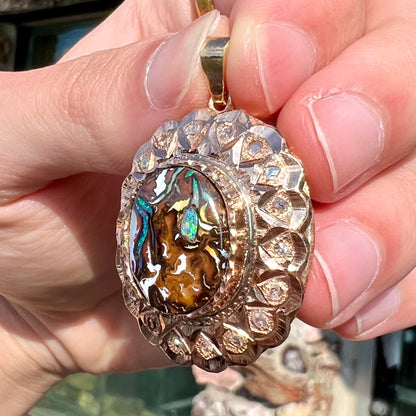 An antique 18 karat yellow gold pendant set with rough diamonds and an oval cut boulder opal from Koroit, Australia.