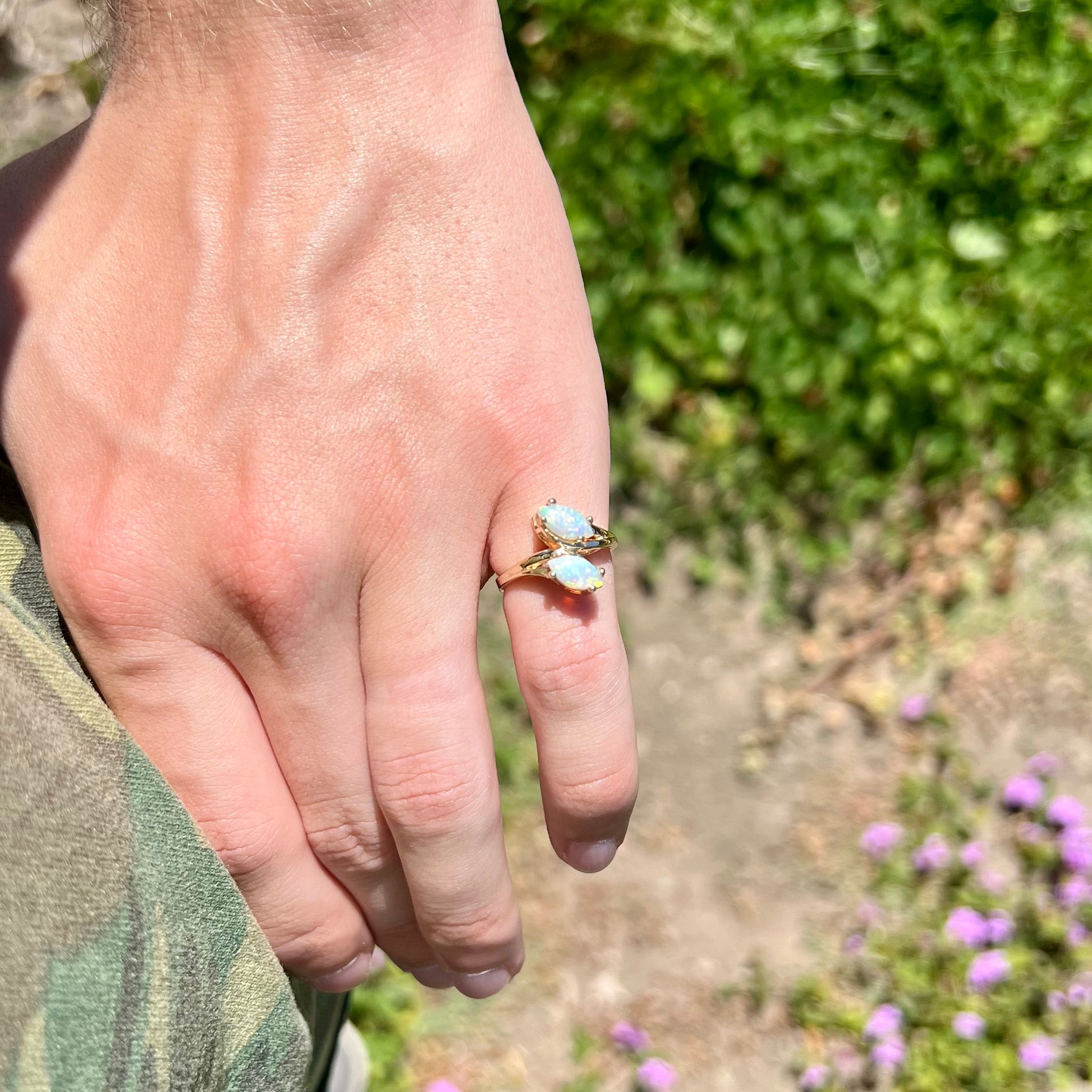 A yellow gold ring mounted with two prong-set marquise cut opal cabochons.