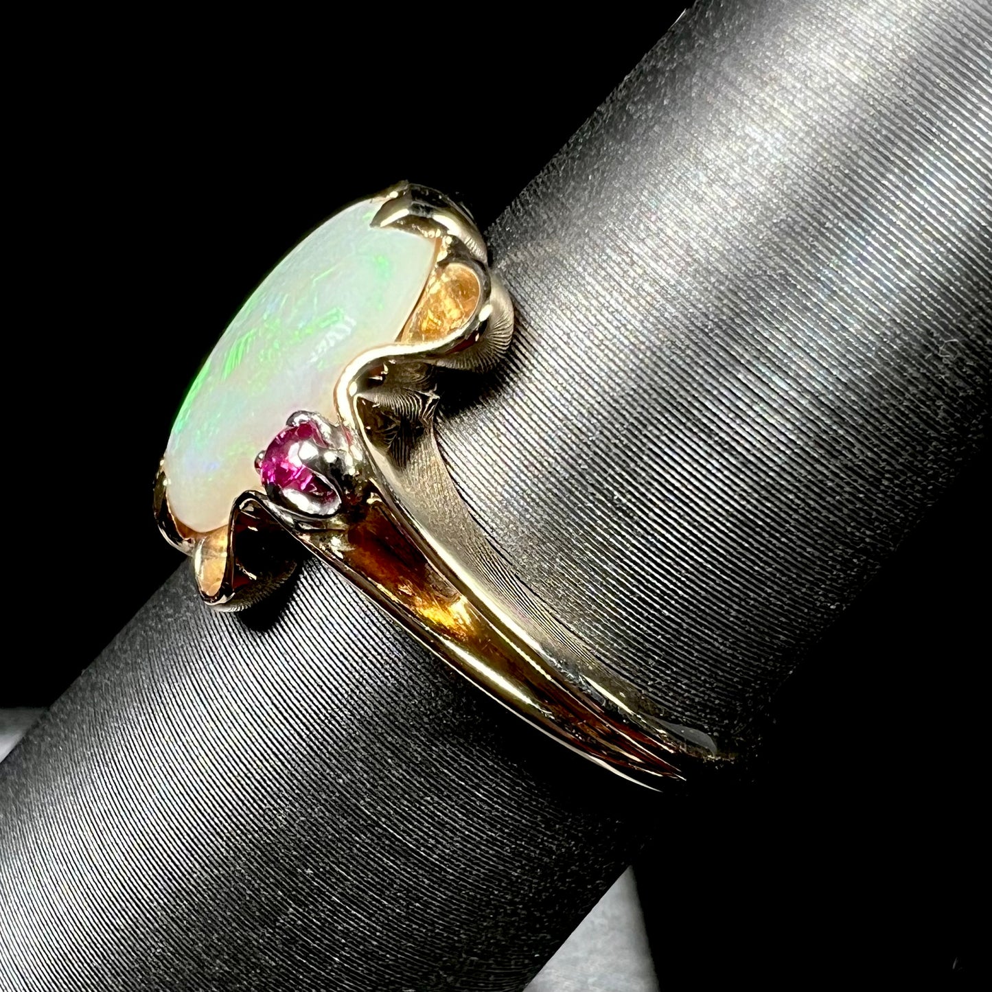 A 1920's Art Nouveau opal and pink sapphire ring.   The ring is yellow gold and palladium.  The opal is green and purple.