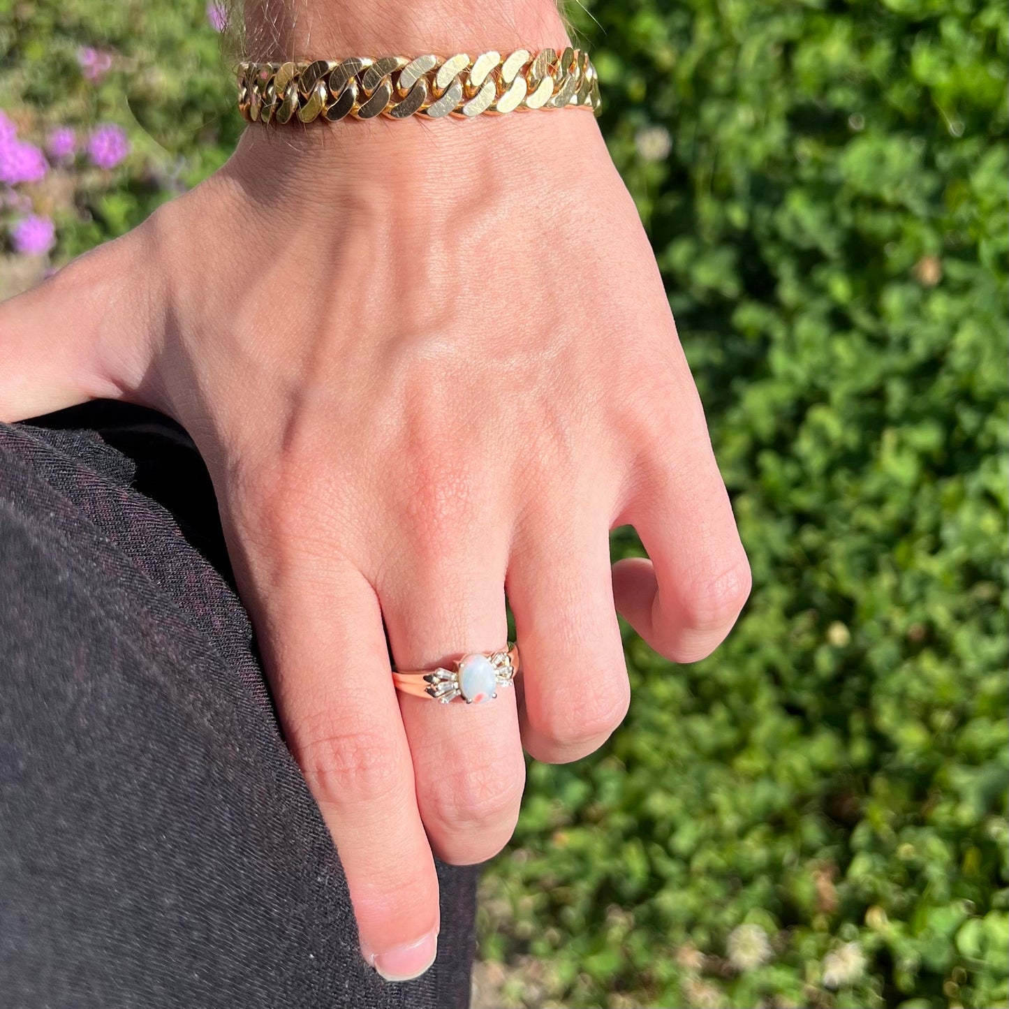 A yellow gold ring set with a natural Australian opal and tapered baguette cut cubic zirconia accents.