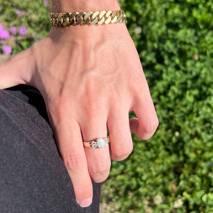 A yellow gold ring set with a natural Australian opal and tapered baguette cut cubic zirconia accents.