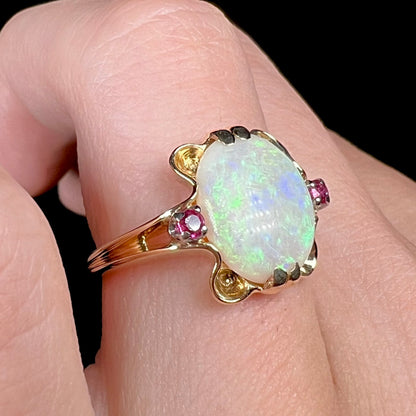 A 1920's Art Nouveau opal and pink sapphire ring.   The ring is yellow gold and palladium.  The opal is green and purple.