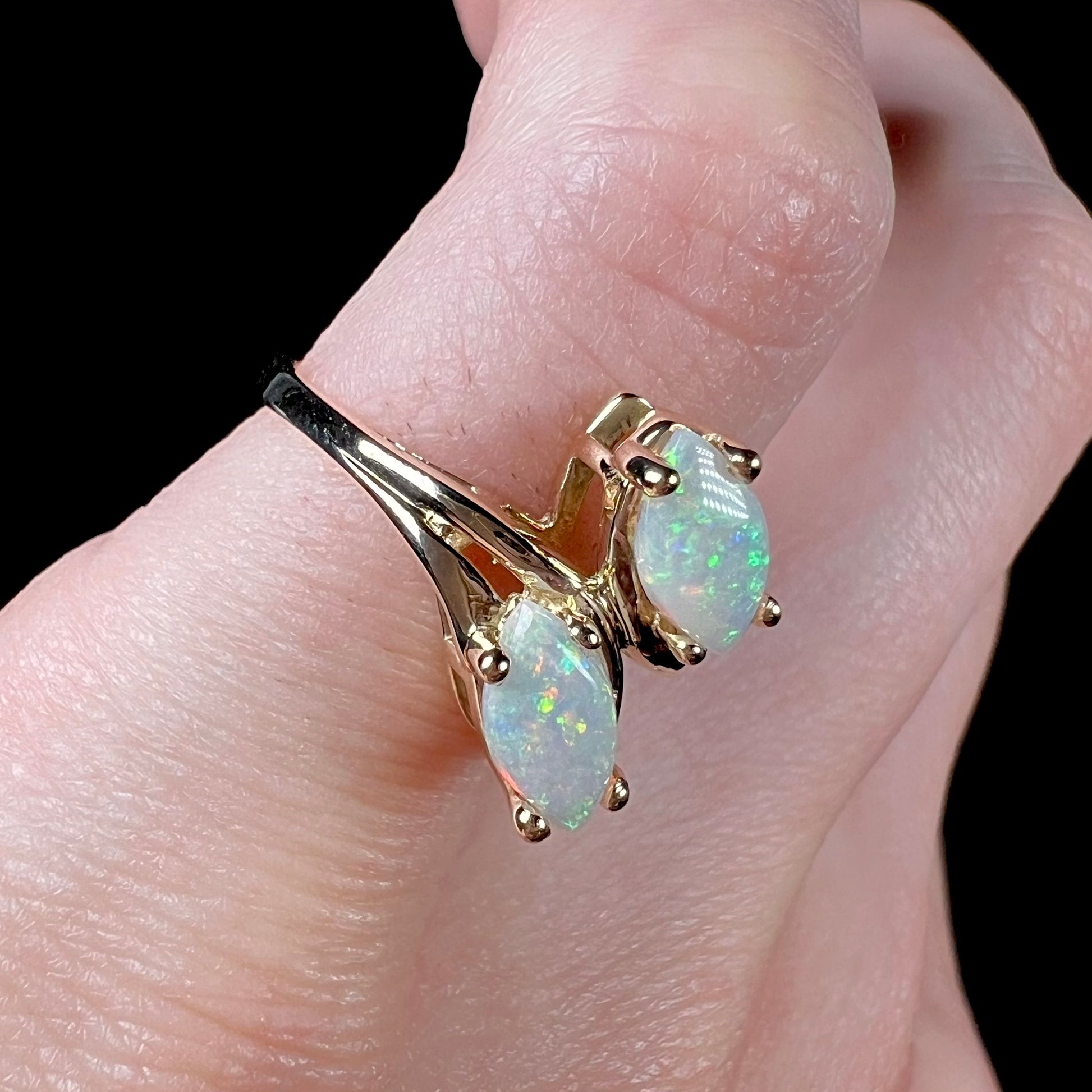 A yellow gold ring mounted with two prong-set marquise cut opal cabochons.