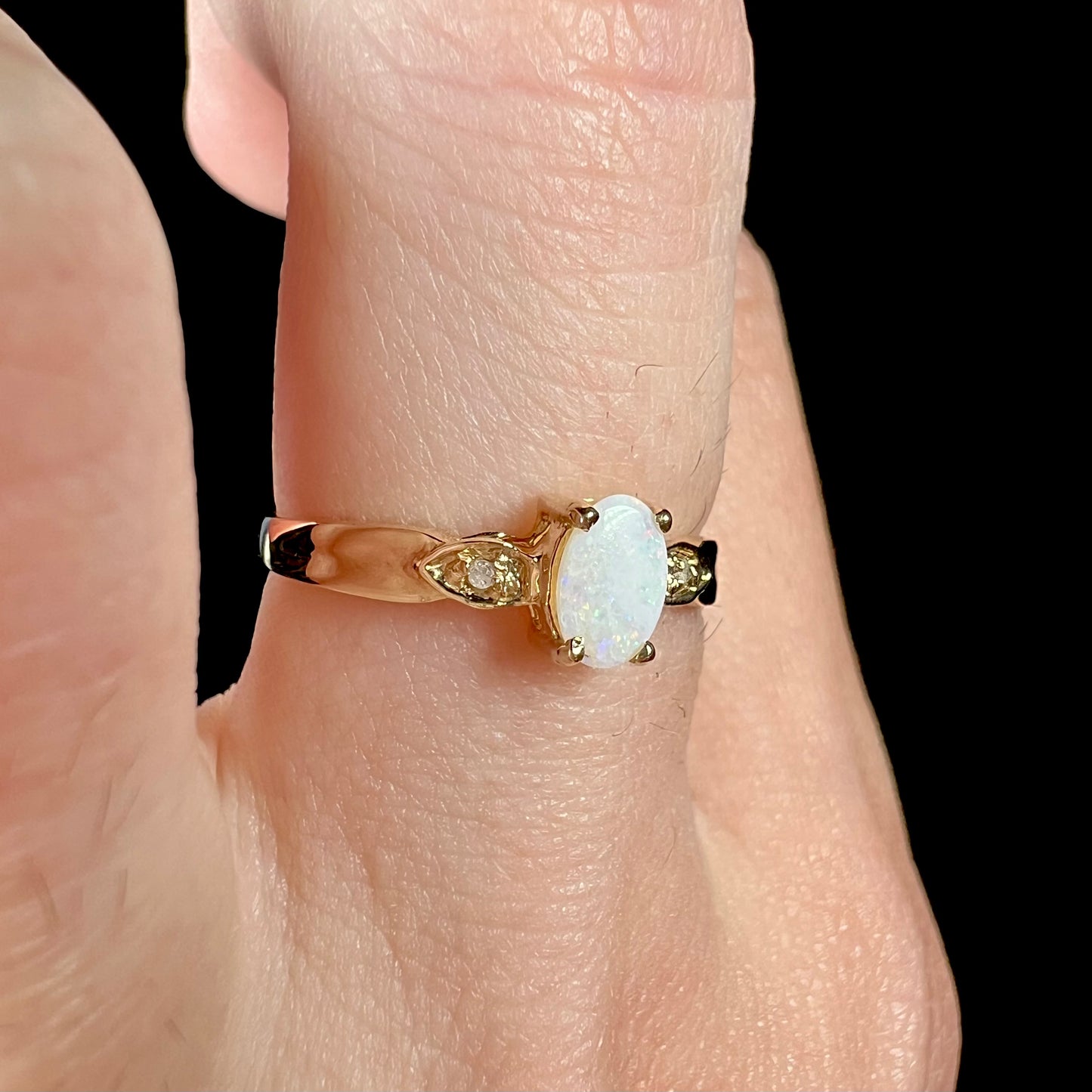 A dainty ladies' yellow gold opal and diamond ring.  The opal has subtle play of color.