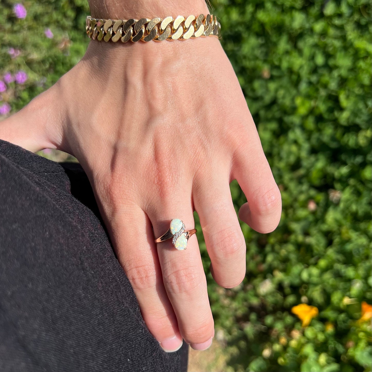 A yellow gold ring mounted with two pear shaped opals and diamond accents  The stones form an infinity shaped design.