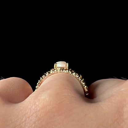 A ladies' yellow gold diamond-cut ring prong set with a natural, marquise cut white opal stone.