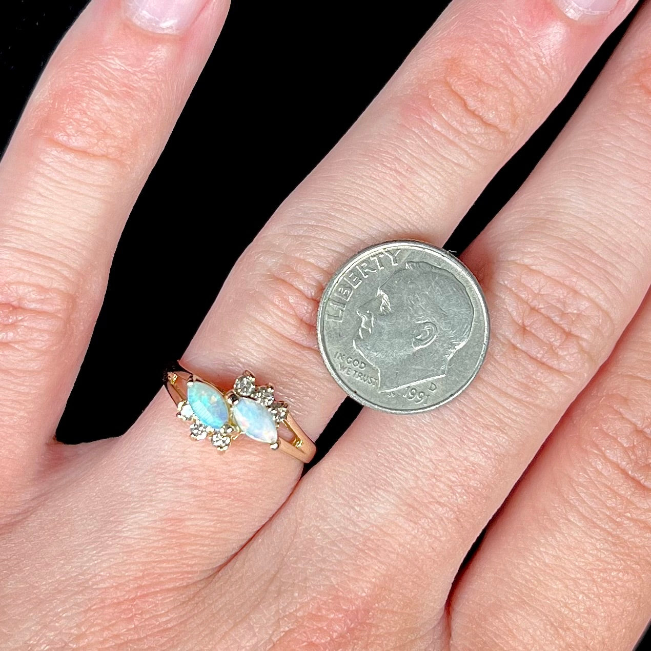 A yellow gold ring mounted with two marquise cut opals and accented with six round diamonds.