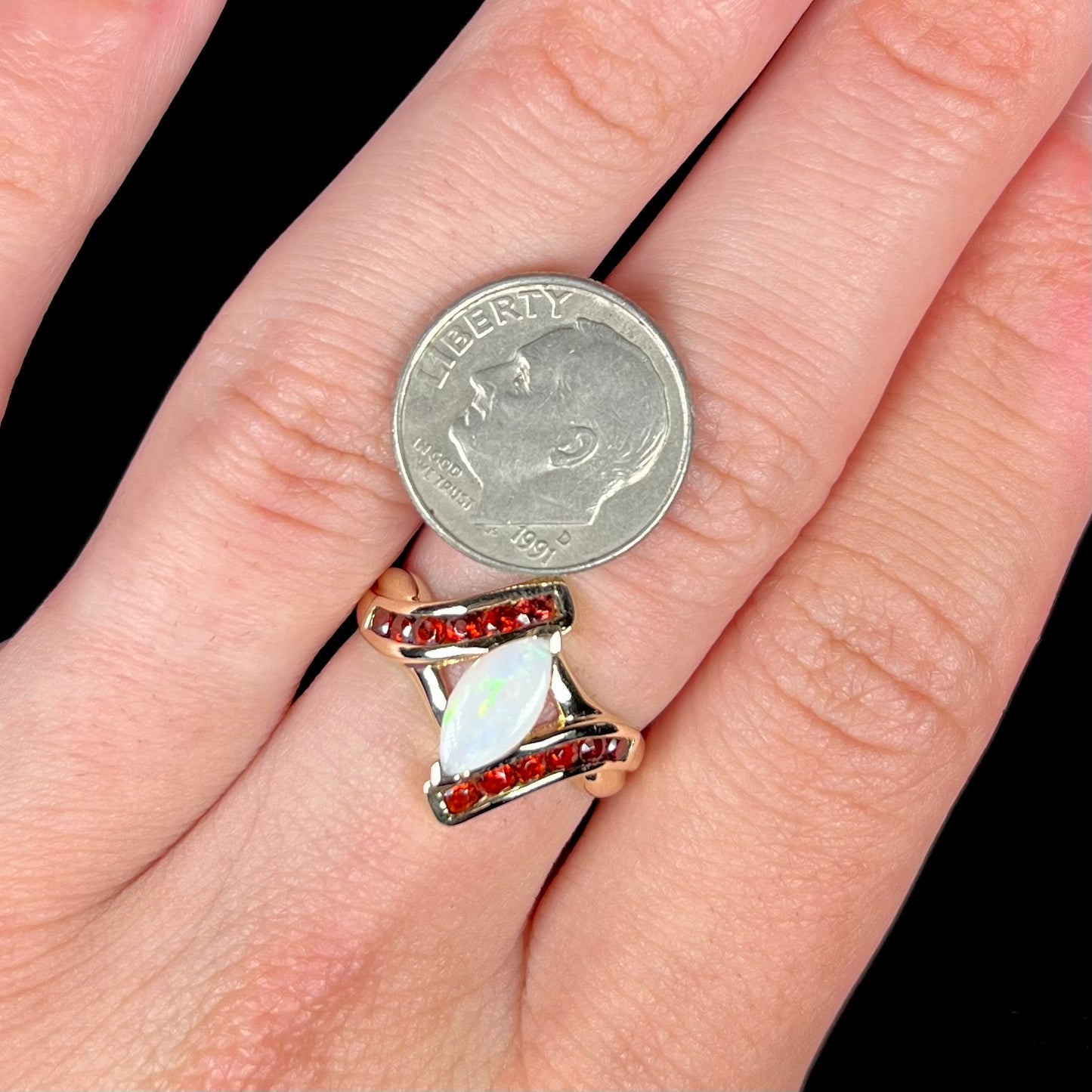 A marquise cut white opal ring.  The ring is accented with channel set reddish orange garnets.